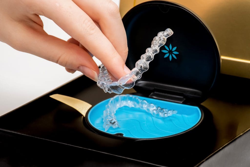Woman's hand removing Invisalign clear aligner from branded case for discreet orthodontic treatment